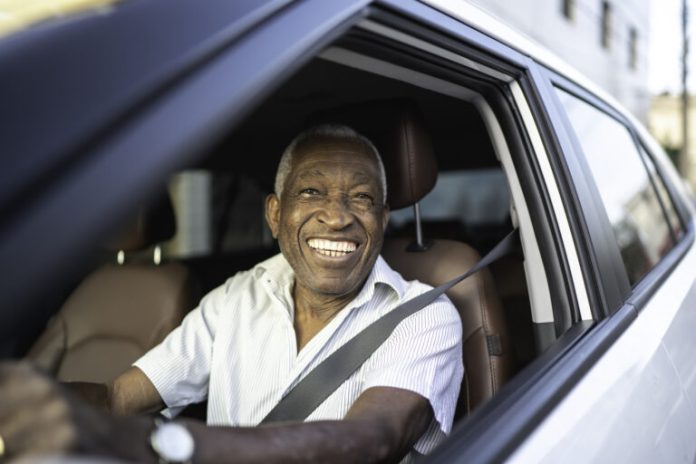 Smiling senior man driving a car and looking at camera